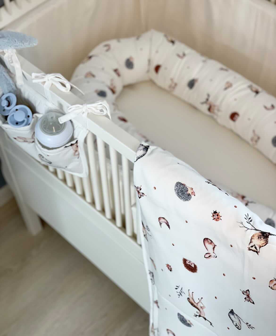 Babynest med skovens dyr i en tremmeseng